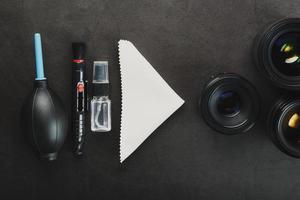 ferramentas para limpar a câmera com lentes em um fundo texturizado escuro. foto