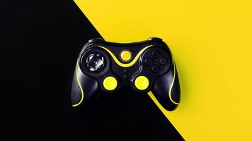 gamepad preto sobre um fundo preto-amarelo, g. conceito de jogo. dispositivo para controlar e controlar o jogo. foto