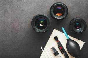 ferramentas para limpar a câmera com lentes em um fundo texturizado escuro. foto