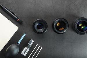 ferramentas para limpar a câmera com lentes em um fundo texturizado escuro. foto
