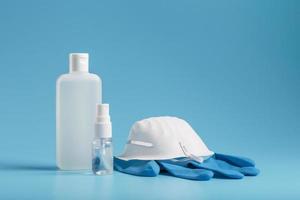 kit de proteção antivírus em fundo azul, máscara, luvas de borracha, frascos de desinfetante para as mãos, gel anti-séptico. foto