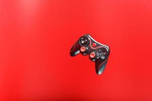 um controlador de jogo joystick preto paira isolado em um fundo vermelho. entretenimento interativo foto