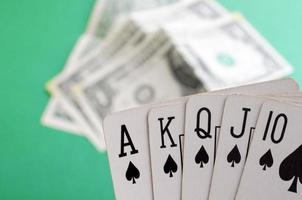 velhas cartas de baralho e dinheiro em um fundo verde. conceito de jogo. combinação de cartas royal flush. perder todo o dinheiro. cartas de pôquer. foto