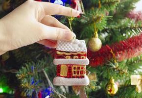 decorar a árvore de natal com brinquedo em forma de casinha. comprar uma casa no ano novo. foto
