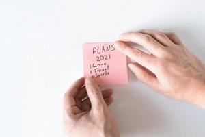adesivo de cola de mãos com planos para 2021. conceito de planejamento. texto no adesivo rosa amor, viagens, esporte foto