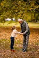 avô passar tempo com sua neta no parque em dia de outono foto