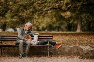 avô passar tempo com sua neta no banco no parque em dia de outono foto