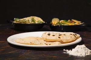 cozinha tradicional indiana chapati ou roti, ou pão indiano em chapa branca com farinha foto