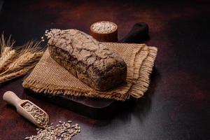 um pedaço de pão integral com grãos de cereais em uma tábua de madeira foto