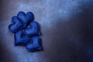 lindos corações de feltro de cor azul em um fundo de concreto azul escuro foto