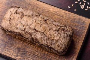 um pedaço de pão integral com grãos de cereais em uma tábua de madeira foto