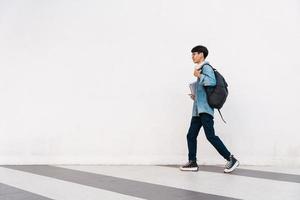 retrato de estudante asiático andando, isolado na parede branca foto