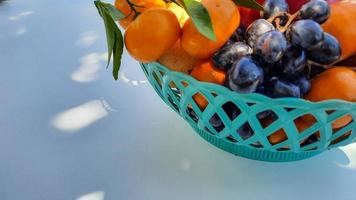 close-up, laranjas de fruta do dragão tropical, peras, uvas em uma cesta verde sobre um fundo branco 02 foto