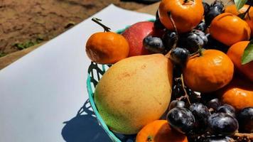 close-up, frutas tropicais de laranjas, uvas e peras na cesta verde sobre fundo branco 03 foto