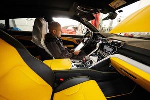 mecânico usando tablet digital, enquanto está sentado no carro esportivo amarelo suv. foto