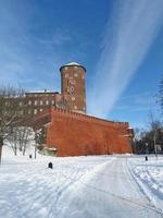 sandomierska torre e parede de tijolos vermelhos embaixo. uma das três torres de artilharia do castelo wawel. em tempos de paz, a torre costumava ser usada como prisão. dia ensolarado de inverno, céu azul, linhas de nuvens brancas. foto