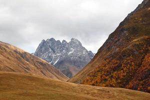 paisagem colorida de outono nas montanhas do cáucaso com pico nevado, geórgia. foto