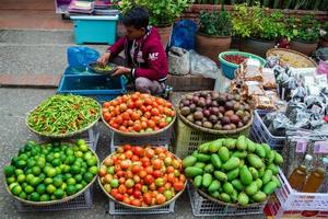 luang prabang, laos - 17 de janeiro de 2018. homem está vendendo frutas, legumes e comida local no mercado de rua. mercado matinal tradicional em luang prabang, laos. foto