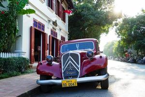 luangprabang, laos - 16 de janeiro de 2018. vista em um clássico carro retrô vermelho em uma rua estacionada perto do restaurante em um tempo ensolarado. foto