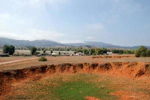 paisagem do campo de crateras de bombas com vila e montanhas ao fundo na província de xieng khouang, laos. um dos lugares mais fortemente bombardeados no laos. foto