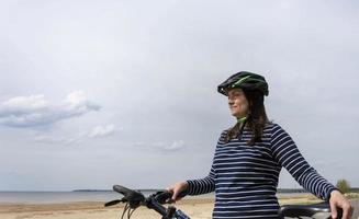 jovem mulher bonita em um capacete de bicicleta com uma bicicleta foto