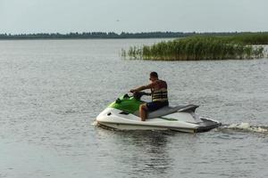 um jovem anda de jet ski no lago, um homem anda de jet ski, estilo de vida ativo, verão, água, calor, férias foto