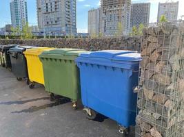 grandes recipientes modernos de plástico preto, amarelo, verde e azul para coleta seletiva e posterior reciclagem ecológica de resíduos em uma nova área da cidade foto