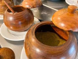 pequenos potes redondos de madeira com colheres de especiarias e temperos em um café ou cantina foto