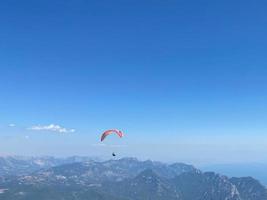 instrutor tandem de parapente amarelo com um turista voando para o céu com nuvens em um dia ensolarado foto