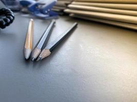 três lápis estão bem afiados ao lado de pastas com folhas de papel e documentos na mesa de trabalho do escritório. papelaria foto