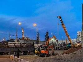 construção de uma ponte quebrada em uma estrada movimentada. caminhões pesados trouxeram uma armação de metal para o viaduto. máquinas de construção carregam blocos de concreto foto