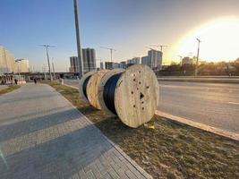 meadas de madeira redondas com cabo de eletricidade. o cabo é enrolado em um grande carretel de madeira. canteiro de obras, colocação de cabos subterrâneos para fornecer eletricidade à área foto