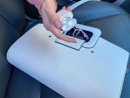 bolsa de couro elegante feminina branca bonita e óculos de sol com fones de ouvido sem fio e mão feminina no carro foto