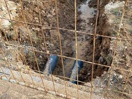 um poço escavado é uma vala para a colocação de cabos e fios com canos sob o solo durante a construção e reparo de casas na cidade da megalópole foto