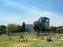 atividades de playground infantil em área residencial, banco comprido cercado por pinheiros, pôr do sol no gramado no texas, nós. escadas, escorregador, balanço para crianças no playground moderno. conceito de bairro urbano foto