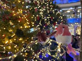 decoração festiva da árvore de natal. pássaro de brinquedo de veludo rosa e fundo com flores artificiais poinsétia como um símbolo de natal foto