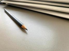 um simples lápis preto está bem afiado ao lado de pastas com folhas de papel e documentos na mesa de trabalho do escritório. papelaria foto