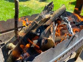 um fogo aceso para carvões em uma grade de ferro enferrujado para cozinhar churrasco e carne frita no fogo foto