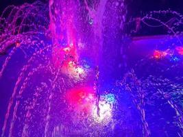 uma bela fonte cantante noturna com jatos de água e salpicos com iluminação multicolorida. o fundo foto