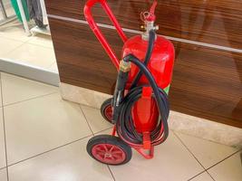 um grande extintor móvel de ferro vermelho com uma mangueira sobre rodas para extinguir incêndios foto