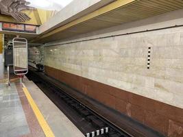 vista do túnel na plataforma de espera de trens na estação de metrô com paredes de granito foto