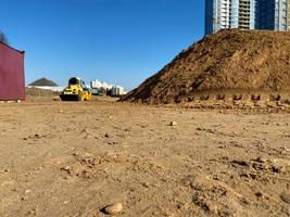 estrada arenosa, perto de uma montanha de areia, virando para cima, tendo como pano de fundo a construção de uma casa foto