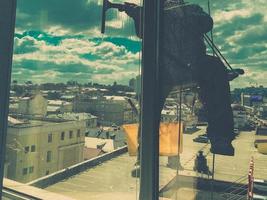 limpador de janelas de alpinista industrial em capacete e luvas lava janelas em movimento de câmera de visão superior de prédio alto foto