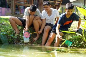 grupo de meninos asiáticos coleta amostras de água e vida aquática para estudar ecossistemas em recursos hídricos comunitários. foco suave e seletivo. foto