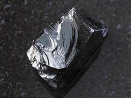 pedaço de vidro vulcânico de obsidiana crua no escuro foto