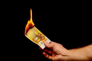 mão segurando a queima de dinheiro em euros foto