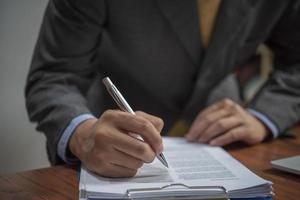 empresário assina documentos com uma caneta fazendo a assinatura na mesa. foto