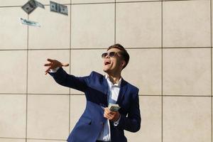 jovem empresário jogando dólares e dançando na rua foto