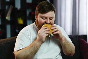 homem grande comendo um hambúrguer foto