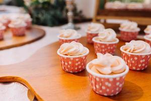 cupcakes gourmet com cobertura de creme de manteiga branco e confeitos em fundo de madeira foto